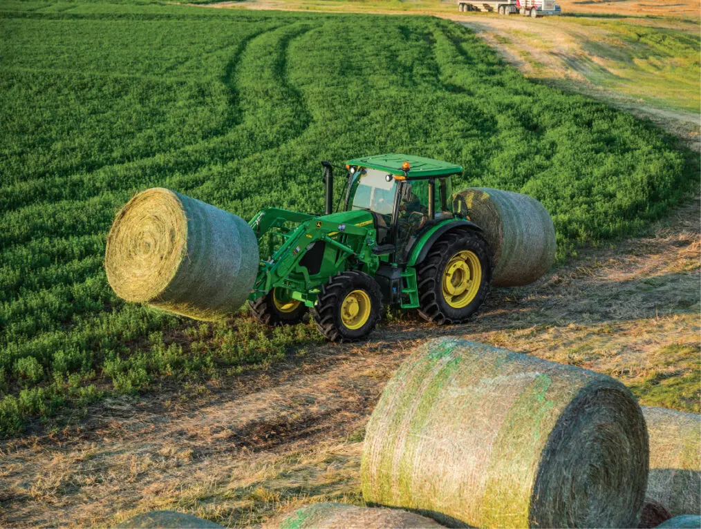 John Deere 6E tractor moving hay in field