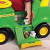 Image of a child playing with the opening seat of the John Deere children's activity Sit 'N Scoot toy tractor.