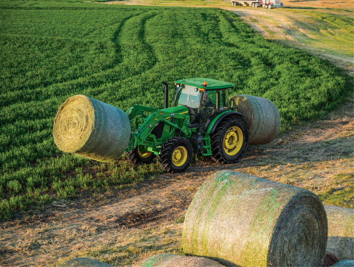 John Deere 6E tractor moving hay in field